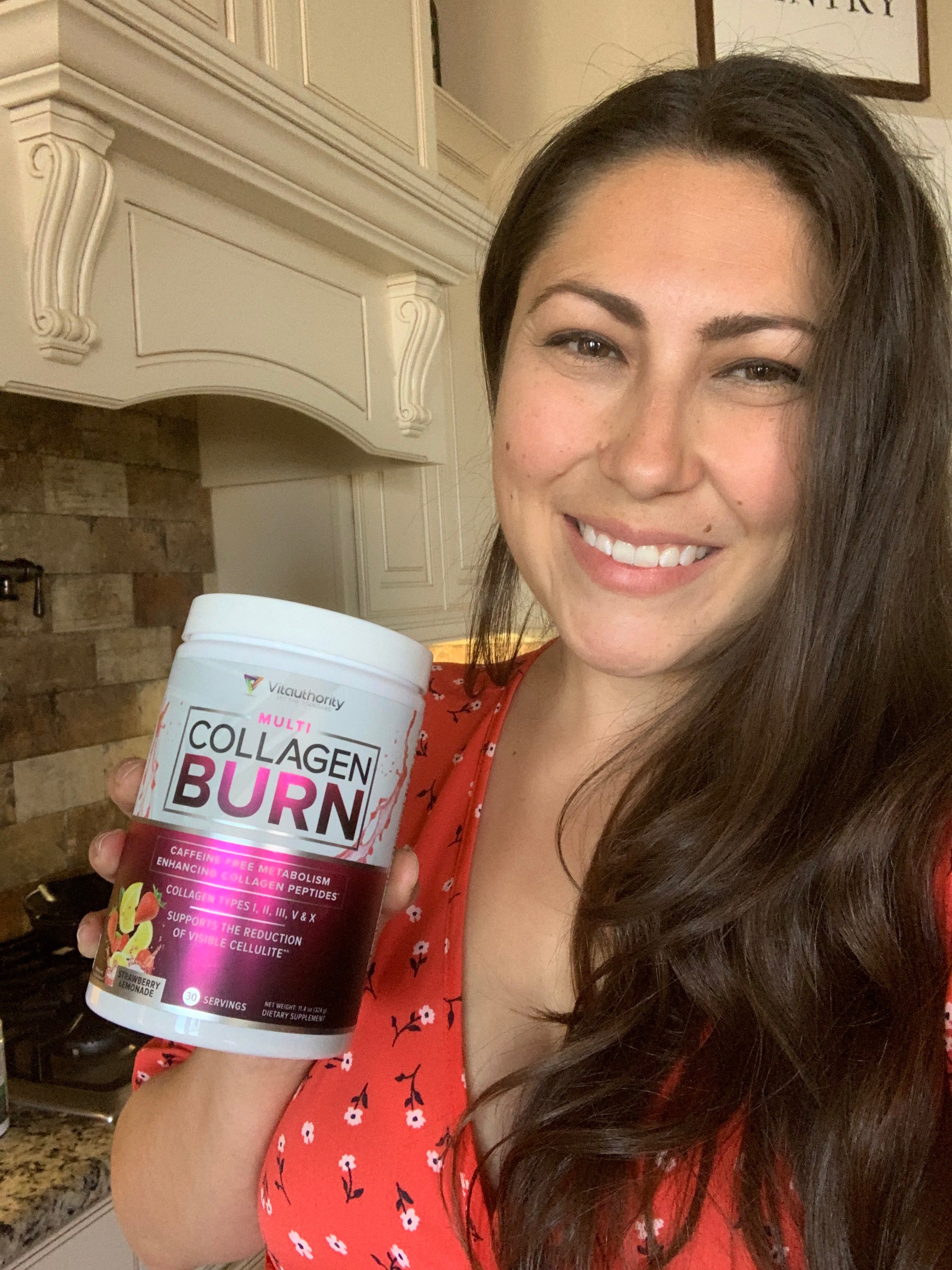 woman in kitchen smiling while holding a multi collagen burn bottle
